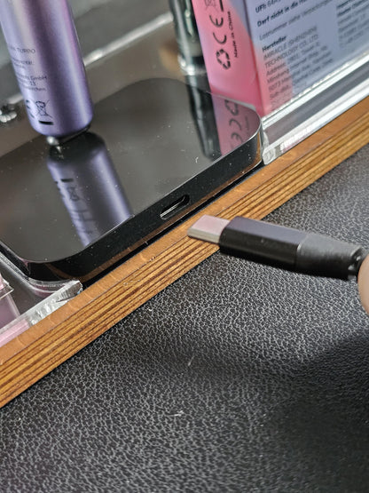 USB-C Kabel wird vor ein schwarzes elektronisches Gerät auf einem Holzständer gehalten