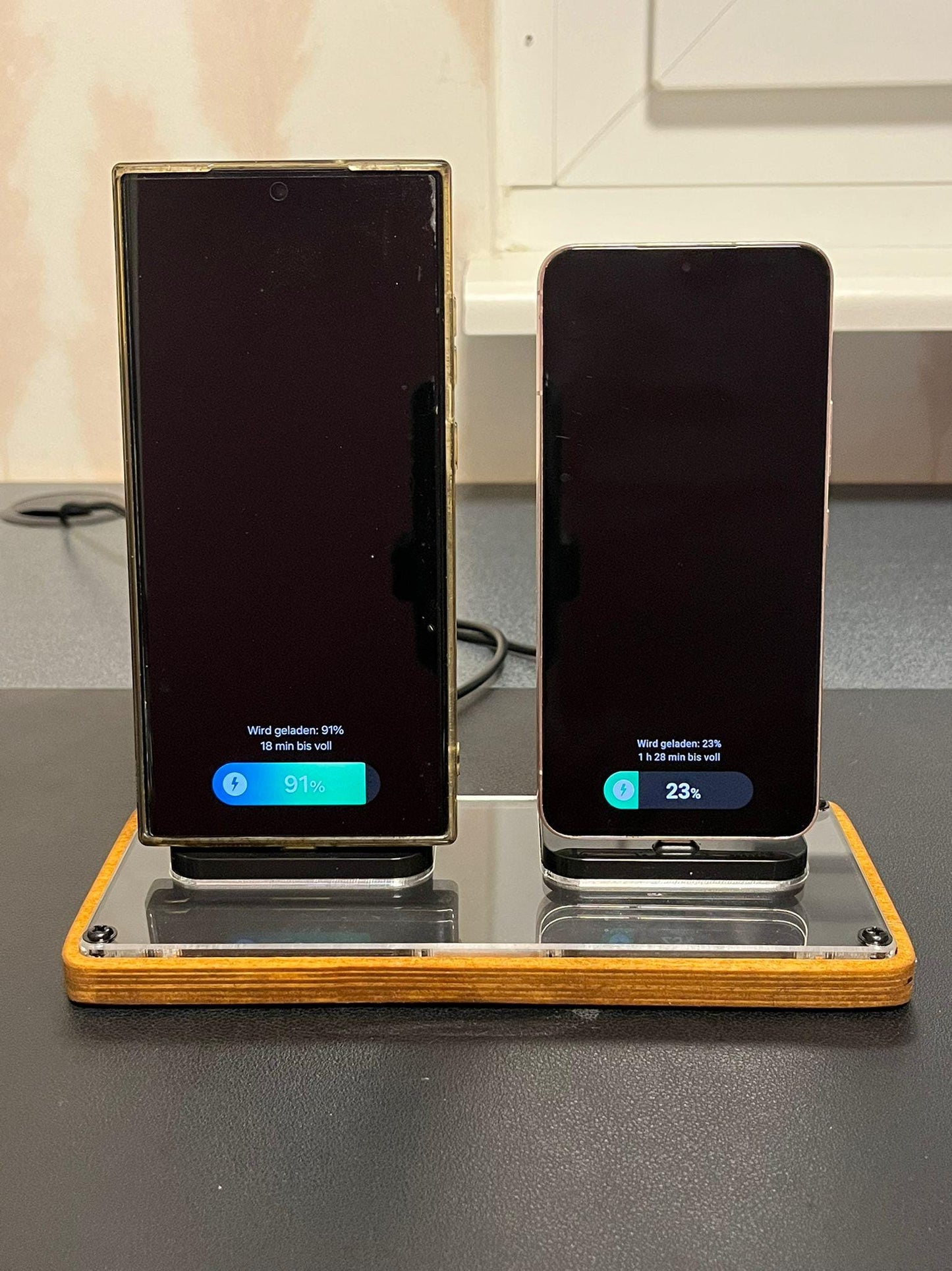 Handy Ladestation aus Holz und Acryl mit zwei Smartphones beim Aufladen