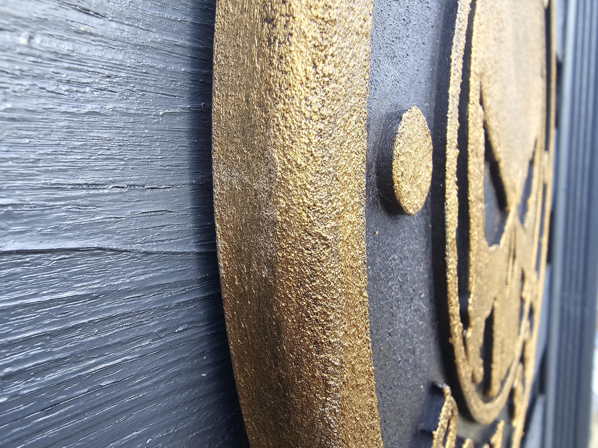 Detail einer goldenen, strukturierten Lasergravur auf schwarzem Holz, Makroaufnahme