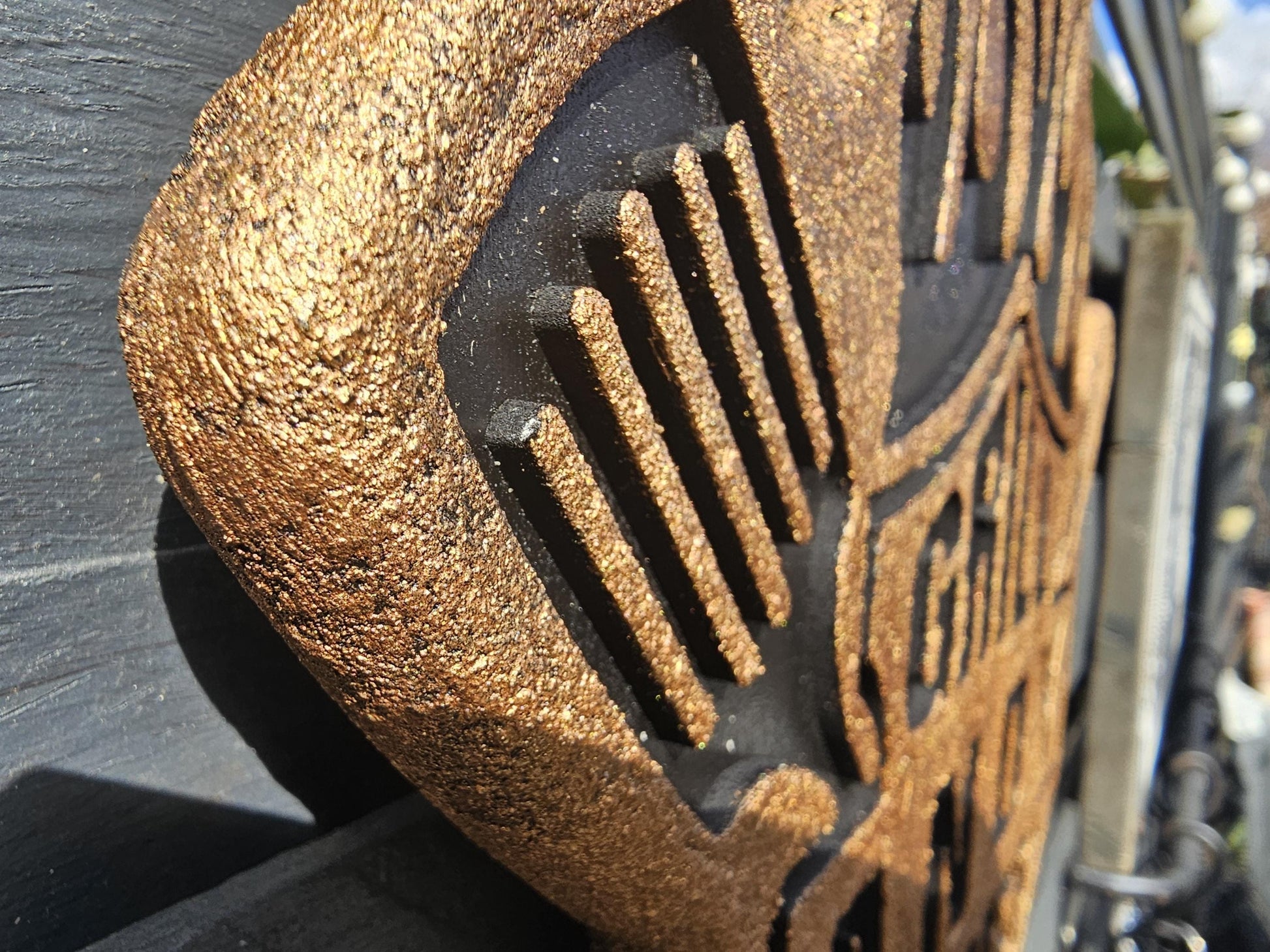 Detailaufnahme einer goldfarbenen, lasergravierten Holztafel mit strukturierter Oberfläche