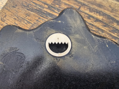 Rückseite einer schwarzen Holzdeko mit Metall-Aufhänger zur Wandbefestigung auf Holztisch