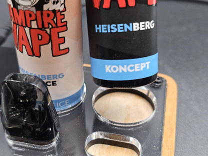 Nahaufnahme von zwei E-Liquid-Flaschen und einem Vaping-Pod in einem Halter aus Holz und Acryl.