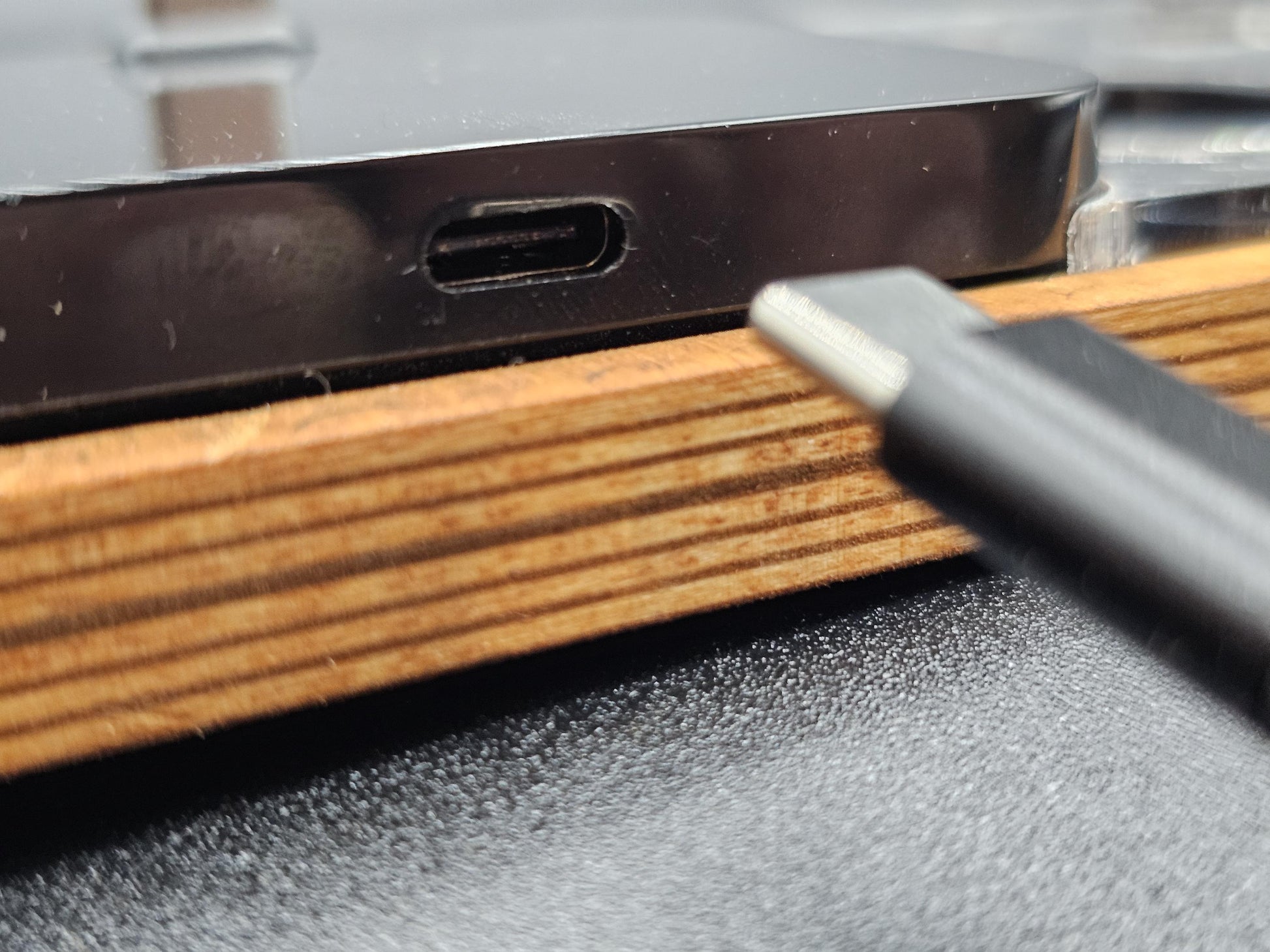 Nahaufnahme eines USB-C-Anschlusses und Kabels, moderne Technik auf Holztisch