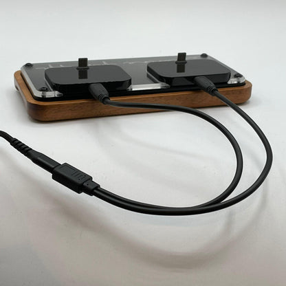 Doppel-Ladestation aus Holz mit zwei eingesteckten USB-Kabeln auf weißem Hintergrund